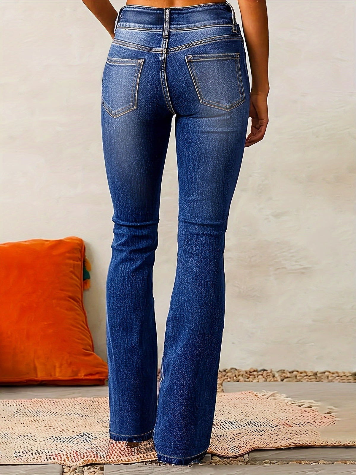 Vista posterior de los jeans azul oscuro, que muestra los bolsillos traseros, la pretina alta y el dobladillo acampanado.
