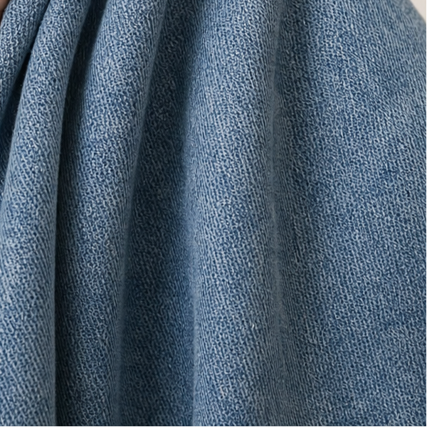 Primer plano de los pliegues y la caída del tejido azul en la pierna curva de los jeans.