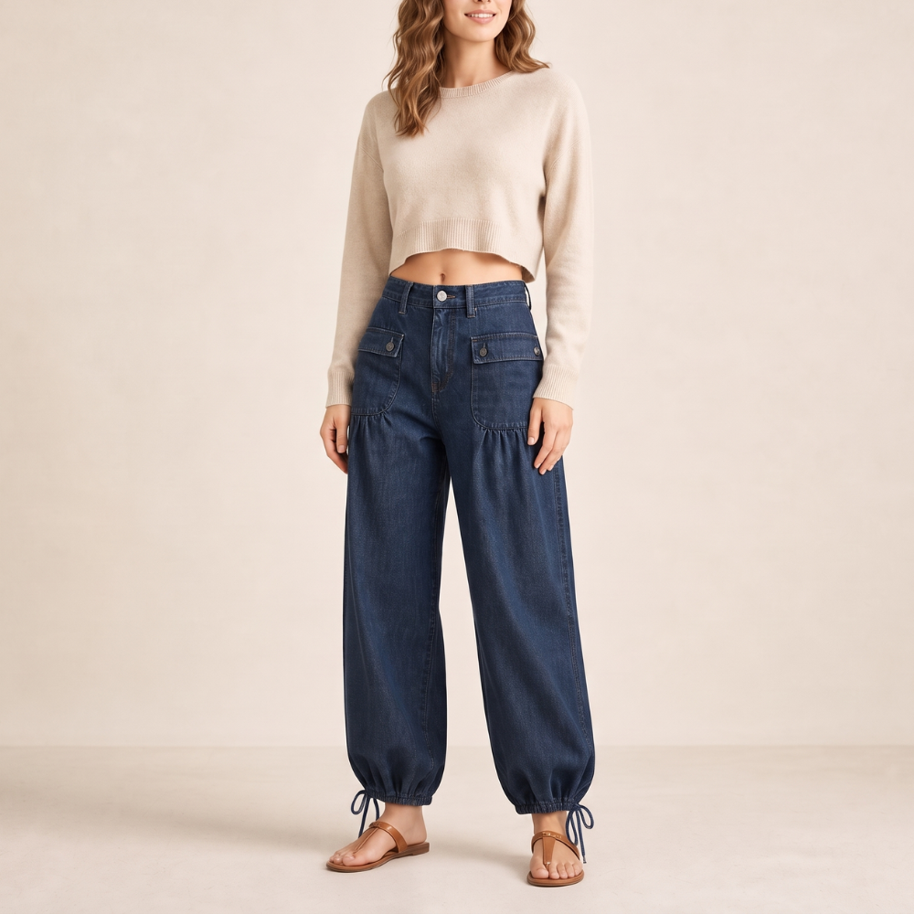 Vista frontal de cuerpo entero de los jeans azules con pierna curva, bolsillos aplicados y lazos en los bajos.