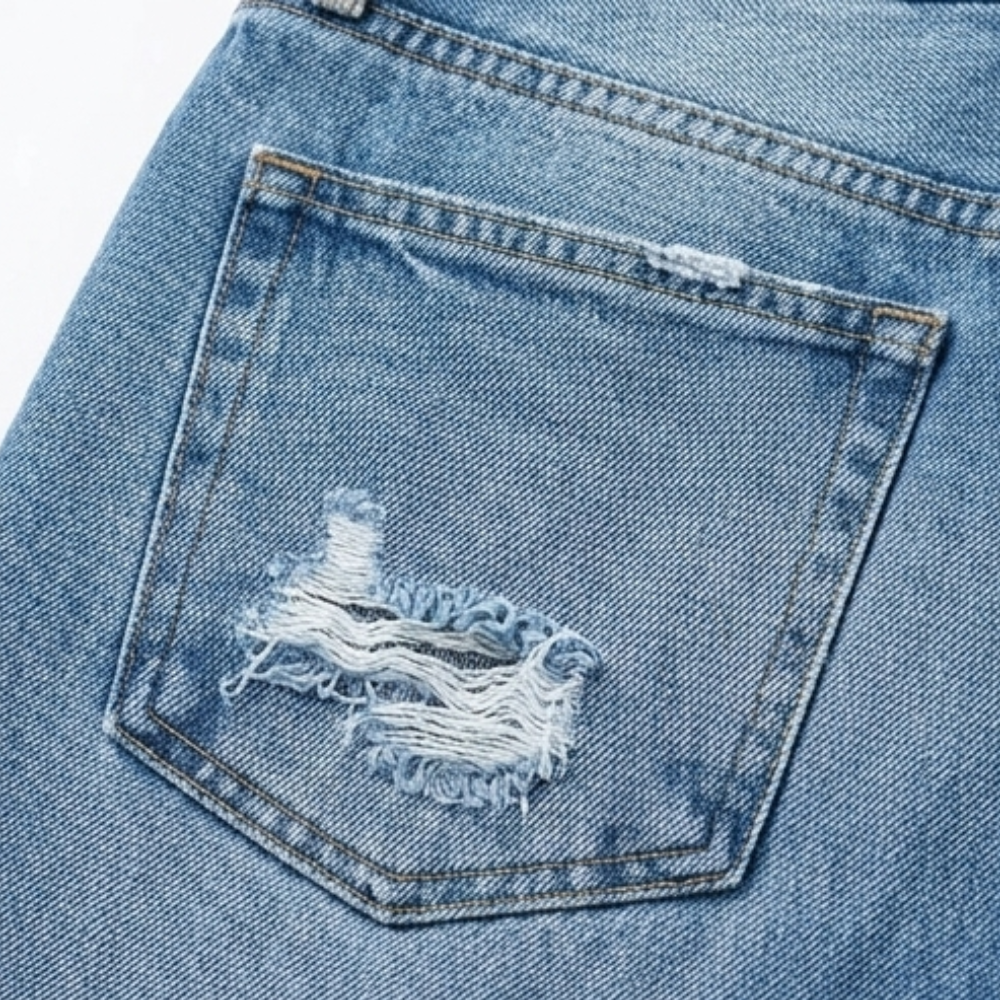 Detalle del bolsillo trasero de los jeans azules con un desgarrado visible.