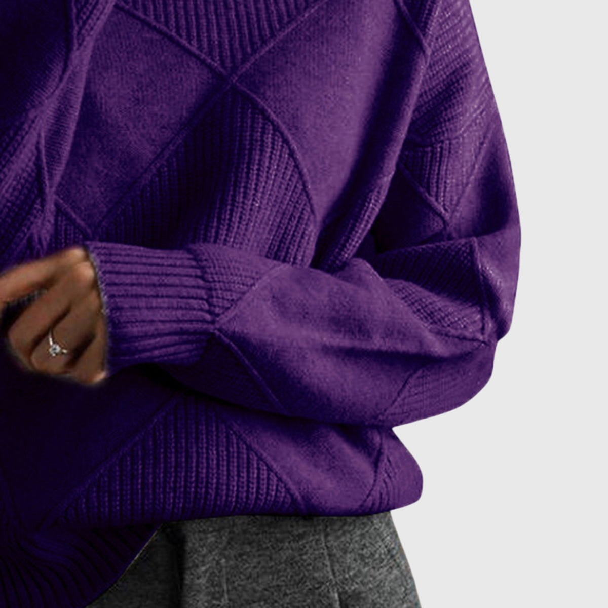 Detalle del jersey morado oscuro con manga doblada, puño acanalado y paneles geométricos en el torso.