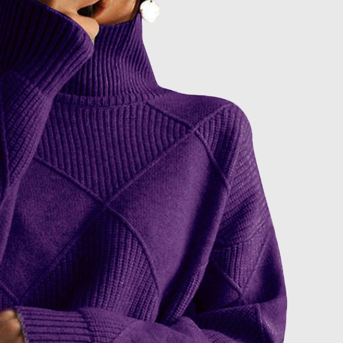 Primer plano de la parte superior del jersey morado oscuro, con cuello alto y líneas geométricas en relieve.