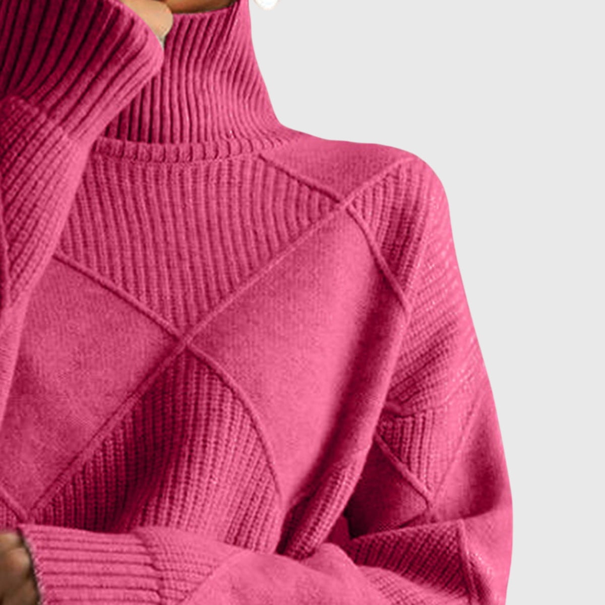 Primer plano del cuello alto y del diseño geométrico en relieve del jersey rosa fucsia.