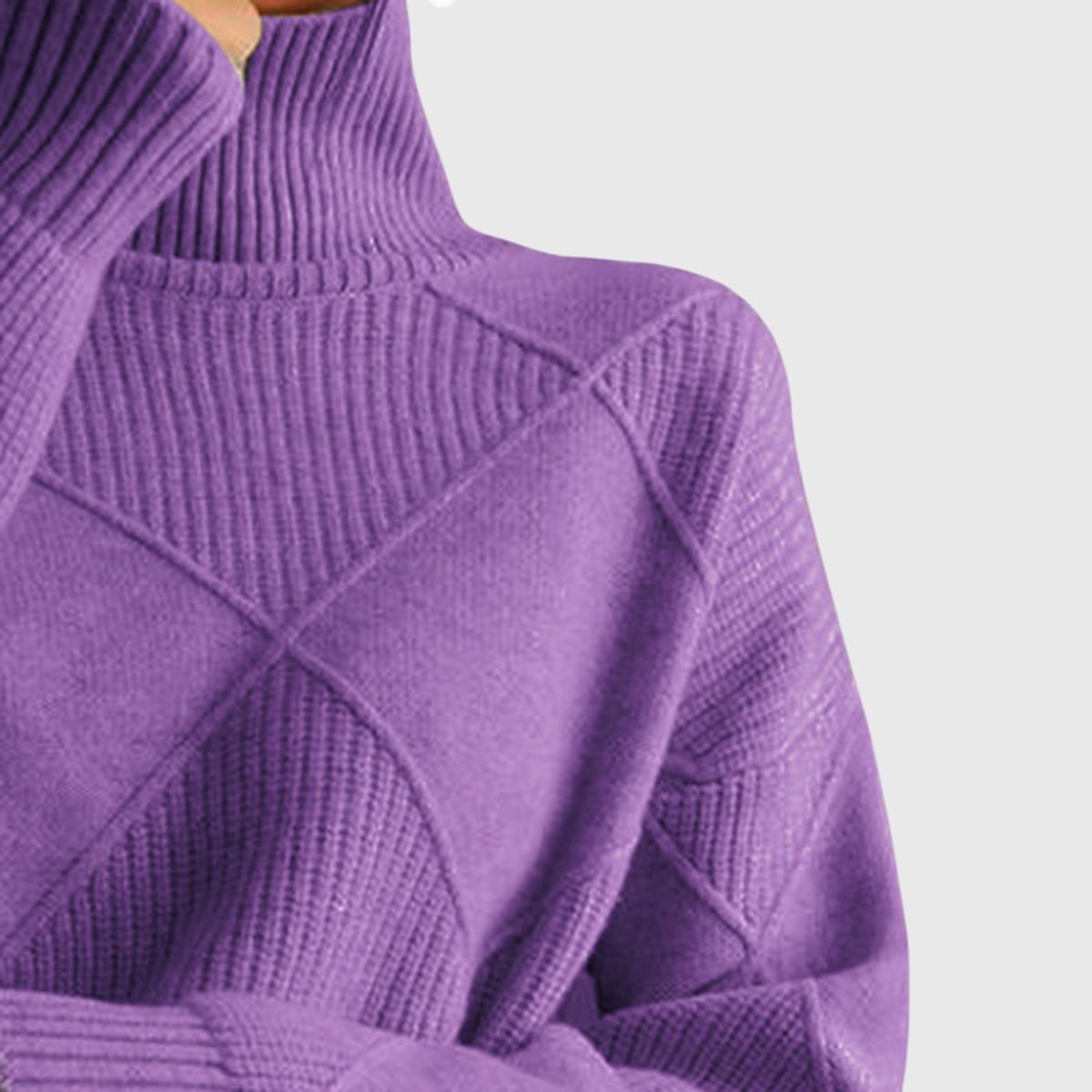 Acercamiento a la parte superior del jersey morado, con cuello alto, hombro y paneles geométricos texturizados.