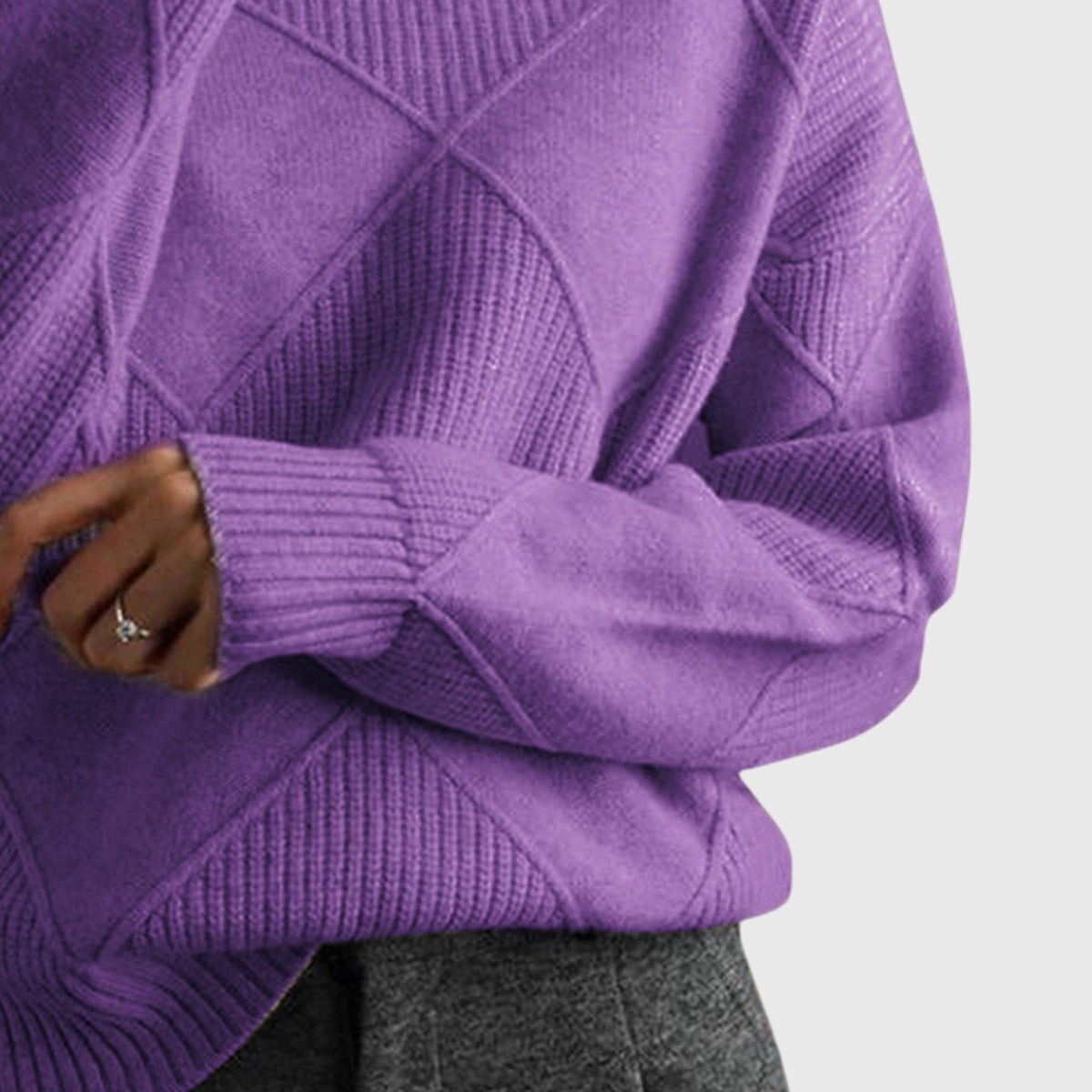 Detalle lateral del jersey morado con manga larga doblada, puño acanalado y relieve geométrico.