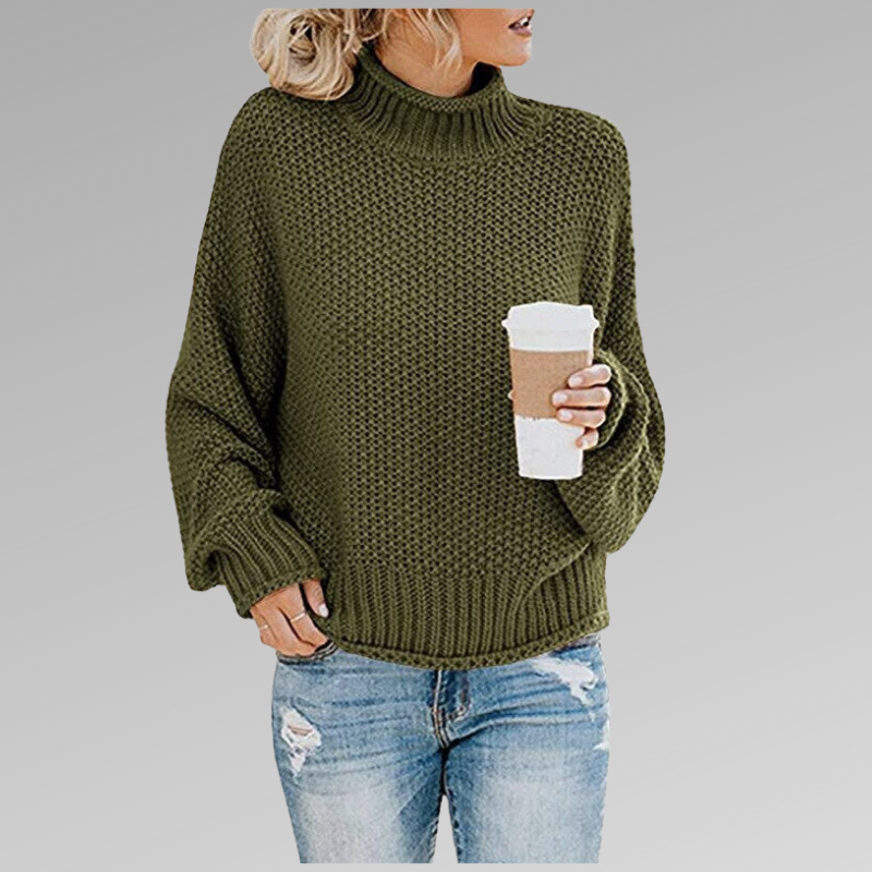 Jersey verde oliva de cuello alto con textura de punto visible, puños acanalados y silueta relajada sobre vaqueros.