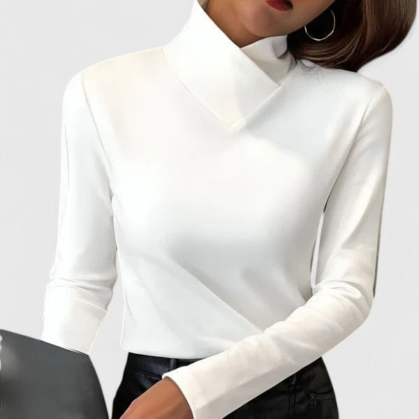 Jersey blanco de manga larga con cuello cruzado, mostrado con pantalón negro y un bolso oscuro.