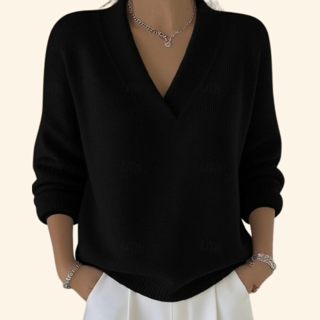 Jersey negro de cuello en V, mangas largas y forma relajada, combinado con pantalón blanco.