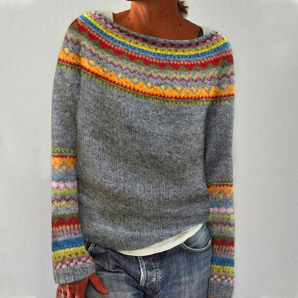 Jersey gris de cuello redondo con bandas geométricas multicolores en el escote y los puños, llevado con vaqueros.