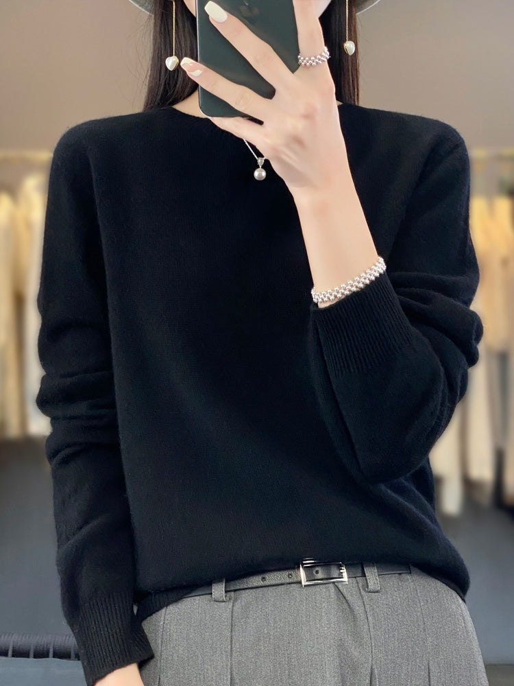 Jersey negro de cuello redondo y puños acanalados, combinado con pantalón gris y cinturón.