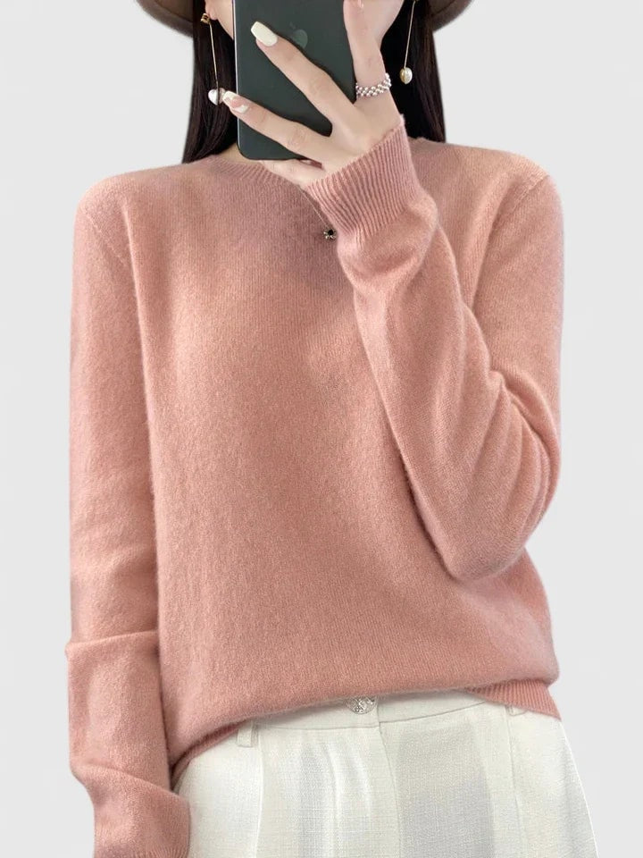Jersey rosa empolvado de cuello redondo, con puños ajustados y pantalón claro.