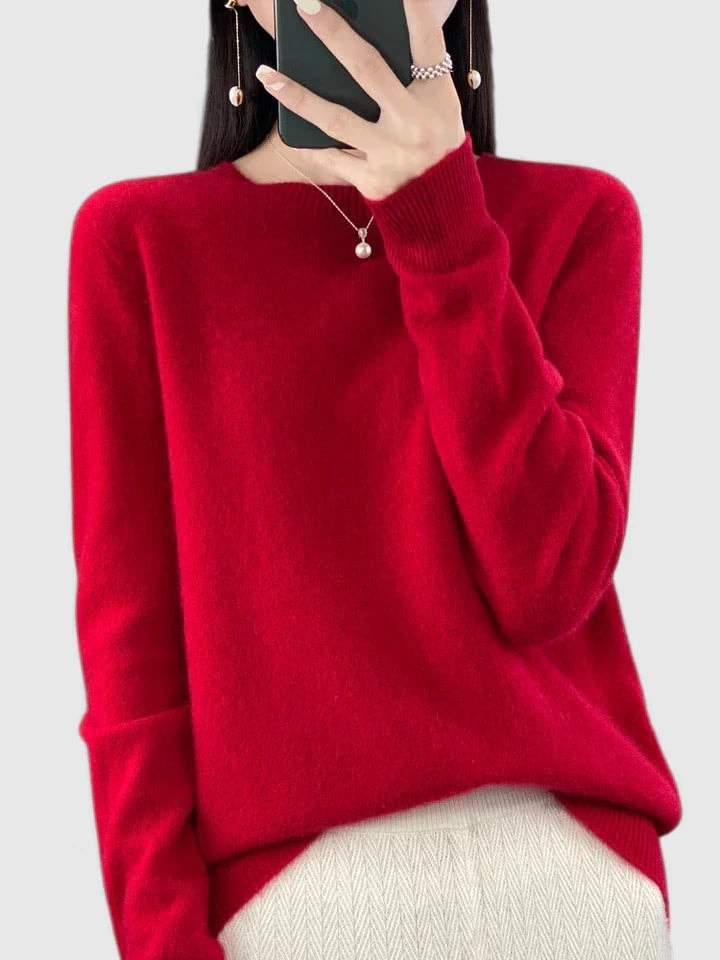 Jersey rojo intenso de silueta amplia sobre fondo claro, con el bajo ligeramente asimétrico.