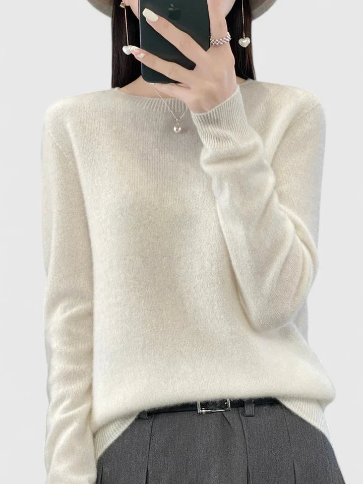 Jersey blanco marfil de cuello redondo, combinado con pantalón gris y cinturón negro.