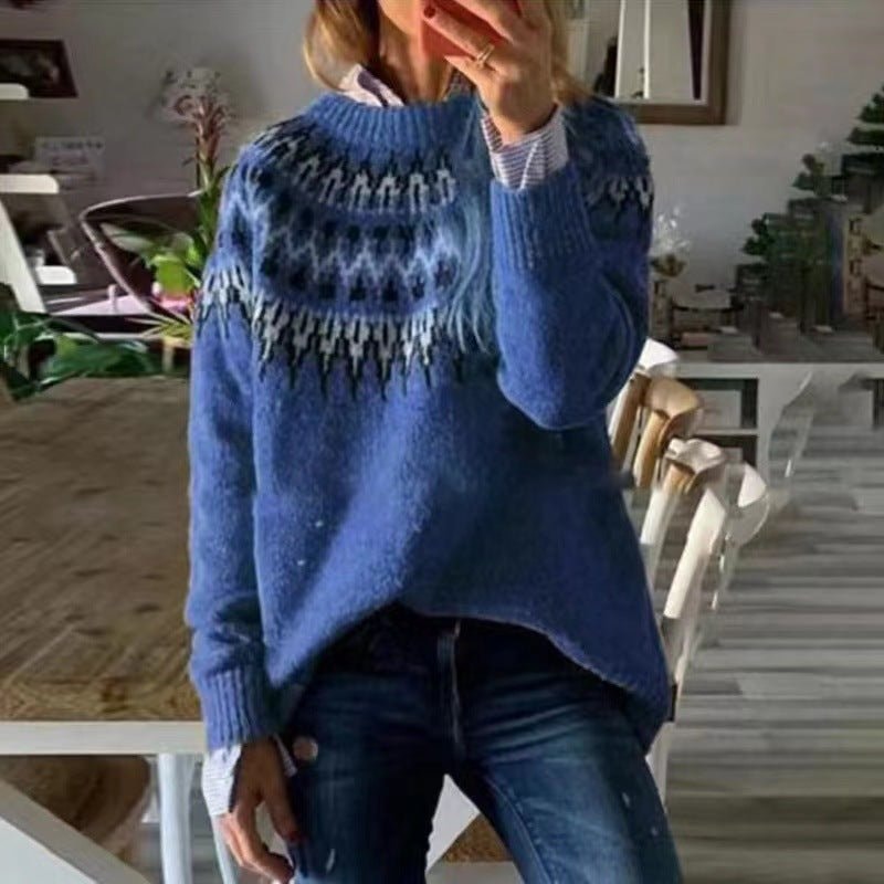 Jersey azul de cuello redondo con diseño nórdico en tonos oscuros, mostrado con vaqueros en un interior.