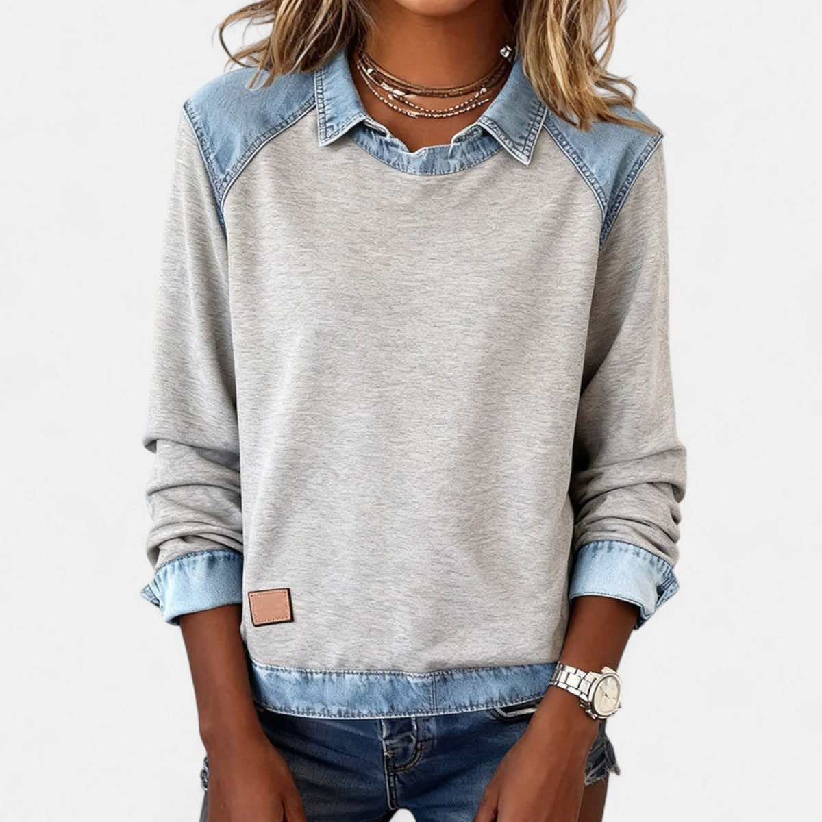 Jersey gris claro de manga larga con efecto camisa superpuesta, visto de frente con los puños remangados.
