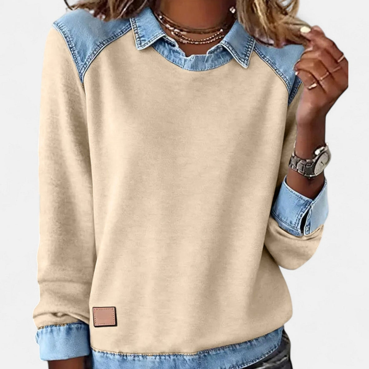 Jersey beige claro de mujer con cuello camisero, hombros y puños azul claro, visto de frente y en primer plano.