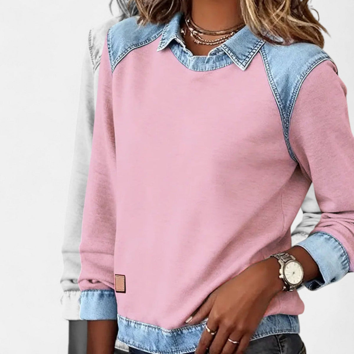 Jersey rosa con efecto camisa superpuesta y detalles azul claro, mostrado en una vista frontal con una mano en el bolsillo.