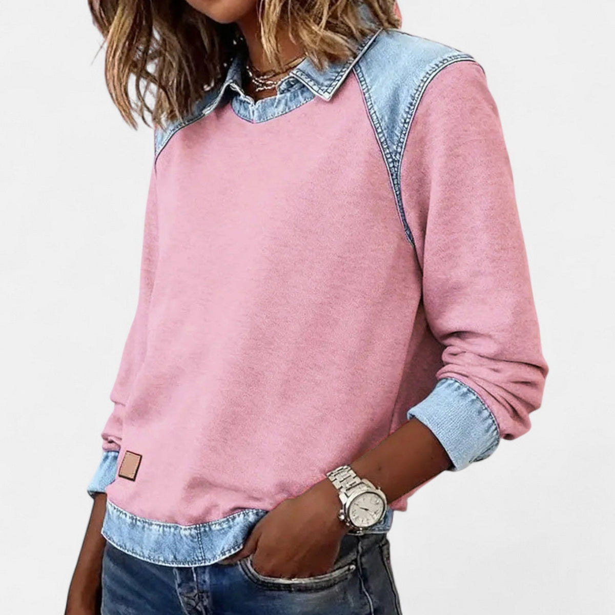 Jersey rosa de manga larga con cuello camisero y paneles azul claro en los hombros, visto desde un ángulo lateral.
