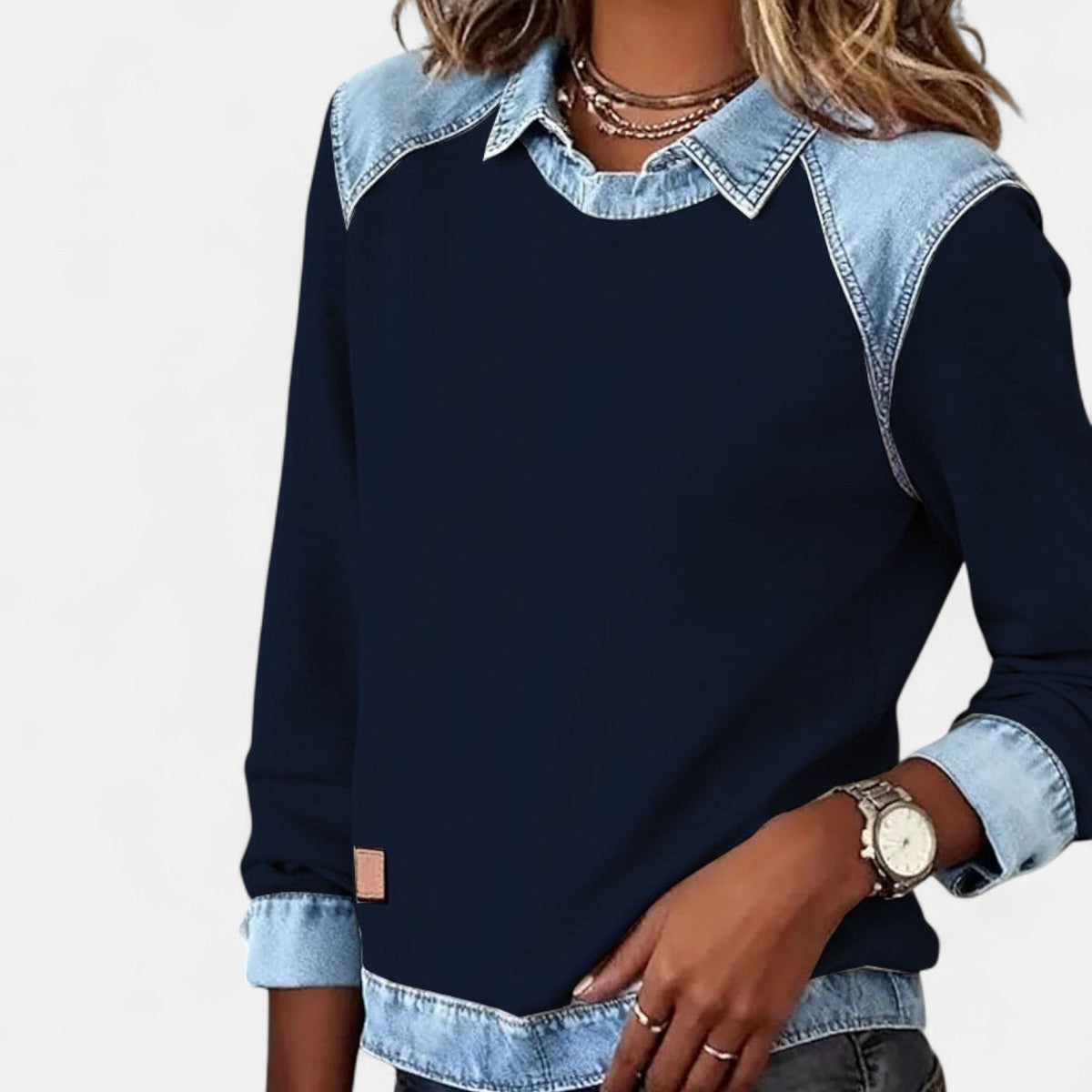 Jersey azul marino de mujer con cuello camisero y puños azul claro, visto de frente en una pose ligeramente ladeada.