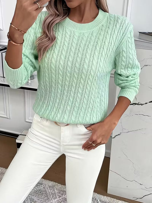 Jersey verde menta de punto calado, con cuello redondo, mangas largas y puños acanalados, combinado con pantalón blanco.