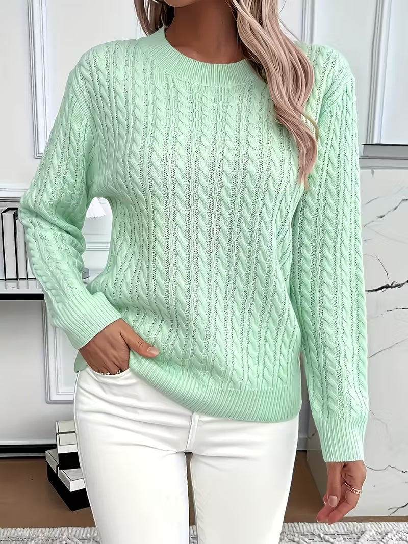 Vista frontal de un jersey verde menta con dibujo vertical calado, cuello redondo y bajo acanalado sobre pantalón blanco.