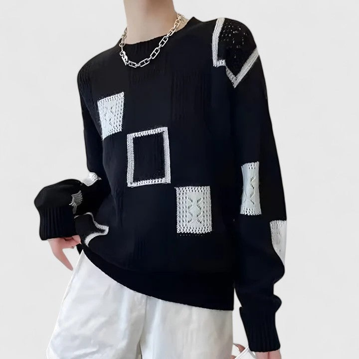 Vista lateral de un jersey negro con cuello redondo, paneles geométricos blancos y puños largos acanalados, combinado con pantalón blanco.