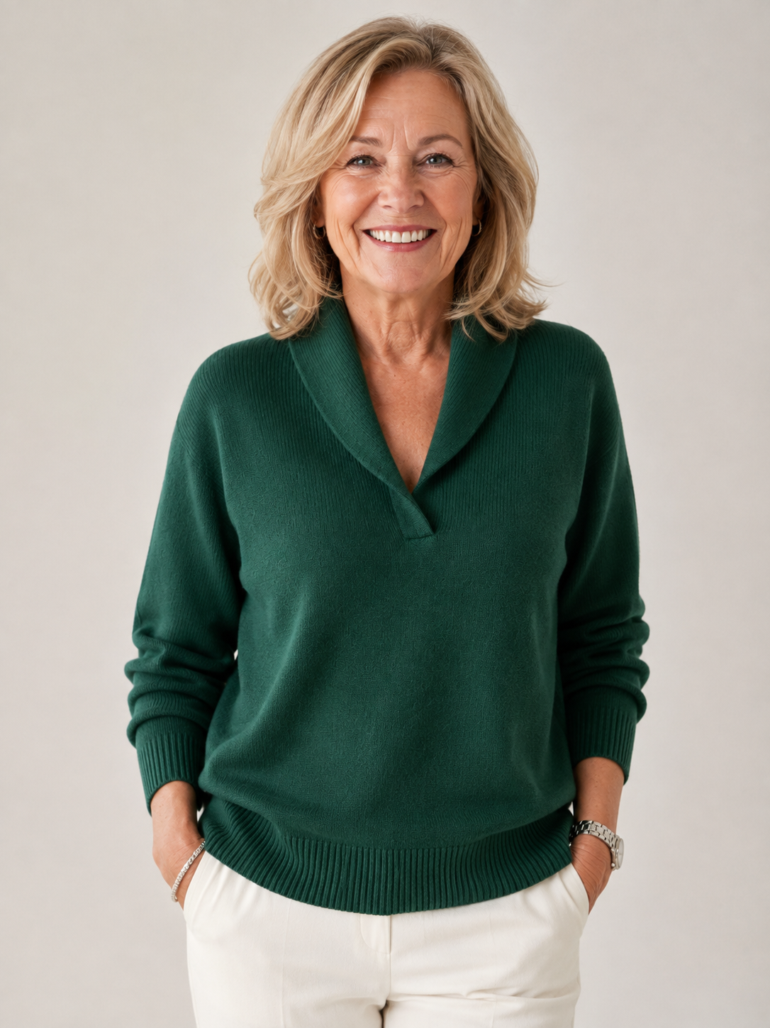 Jersey de punto verde oscuro con cuello chal y manga larga, combinado con pantalón blanco y mostrado de frente en una modelo sonriente.