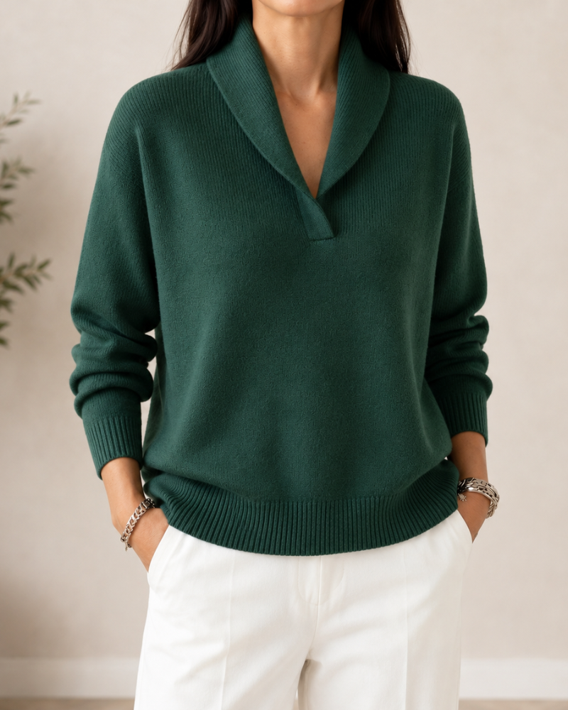 Vista frontal del jersey verde oscuro de cuello chal, con puños y bajo acanalados y las manos en los bolsillos del pantalón blanco.