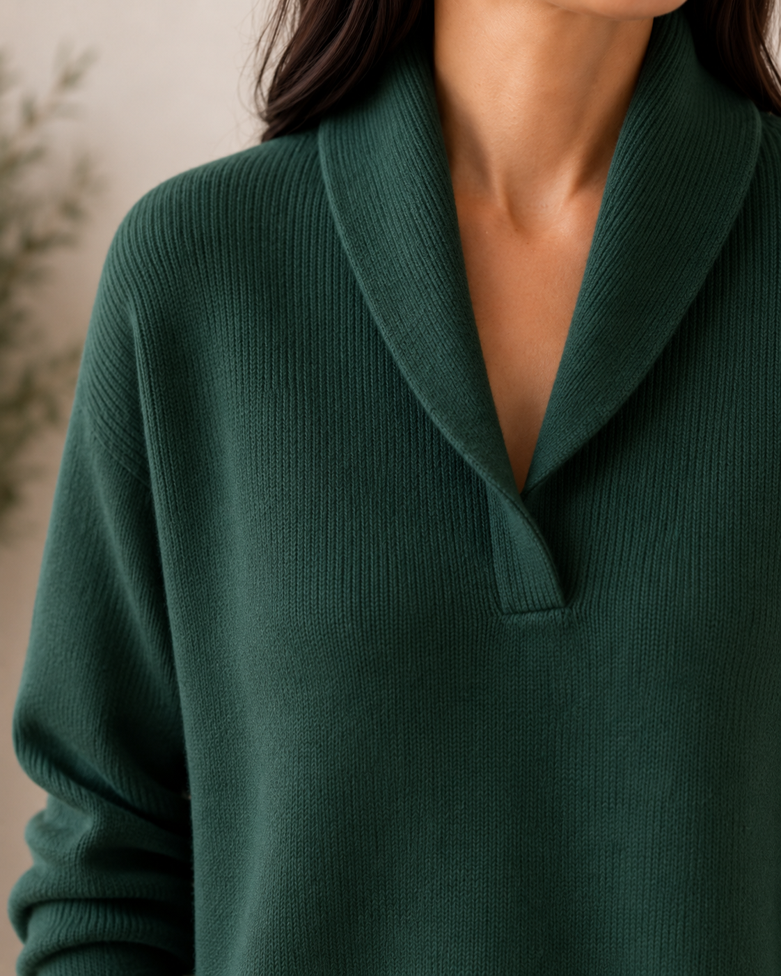 Detalle cercano del cuello chal verde oscuro y la abertura en V del jersey de punto, junto con parte de la manga larga.