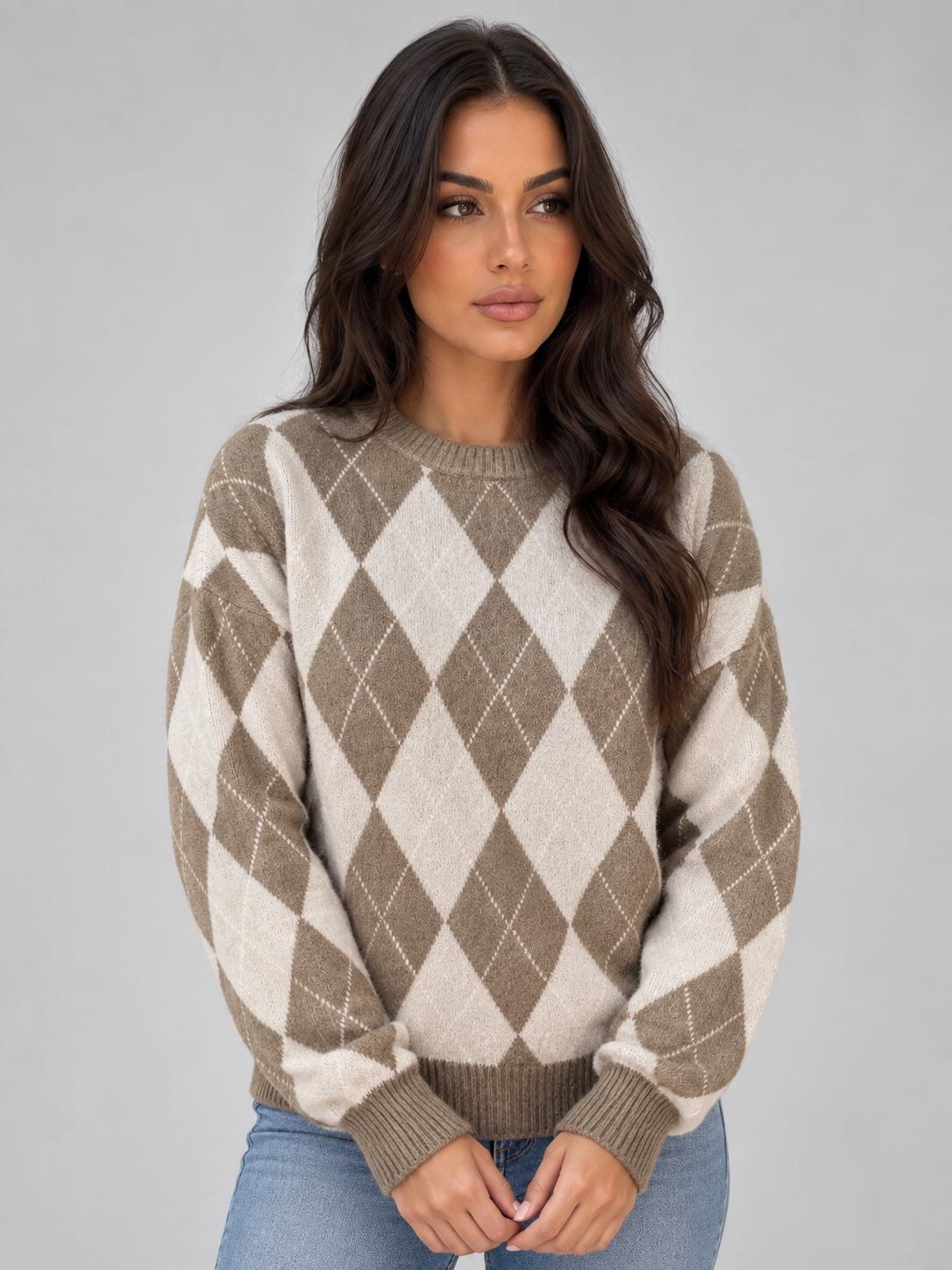 Jersey de rombos en tonos taupe y crema, mostrado de frente con las manos juntas para destacar el cuello redondo y la combinación geométrica.