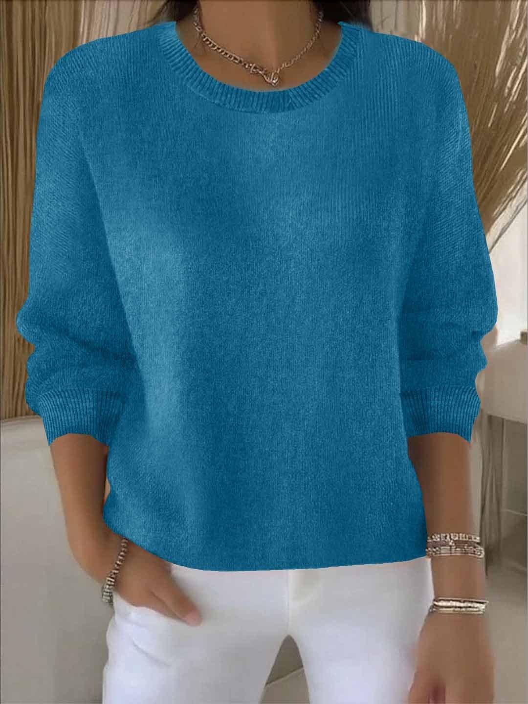 Jersey holgado azul intenso con cuello redondo y puños ajustados, llevado con pantalón blanco.