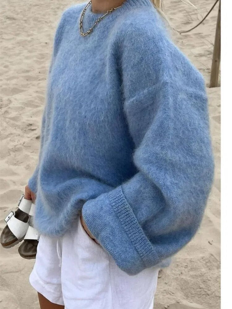 Vista lateral de un jersey azul amplio con hombros caídos y puños anchos, combinado con pantalones cortos blancos.