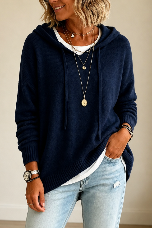 Jersey oversize azul marino con capucha y cordones, bajo asimétrico y mangas recogidas en los puños.