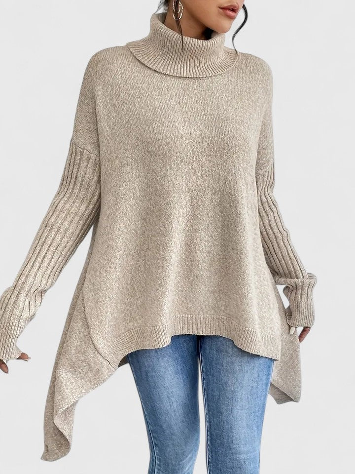 Jersey beige claro mostrado de frente y ligeramente de lado, con mangas largas, cuello alto y extremos laterales del bajo más largos.