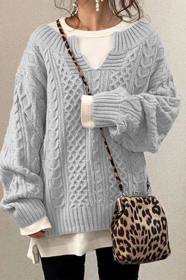 Jersey oversize gris claro con textura de punto trenzado, escote en V y silueta holgada.