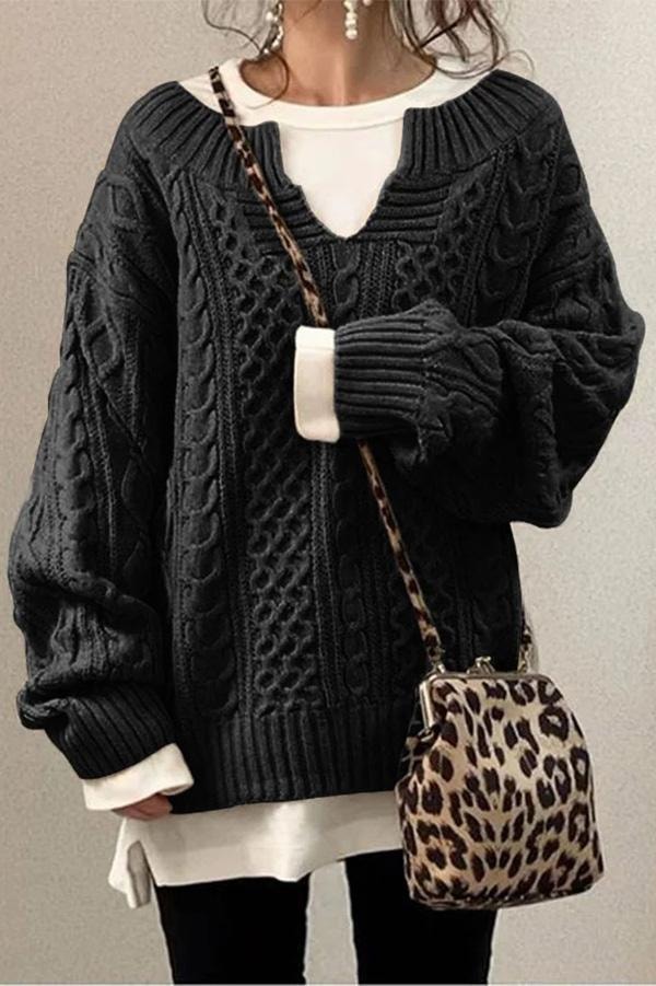 Jersey oversize negro con paneles de trenzas, cuello en V acanalado y mangas amplias recogidas.
