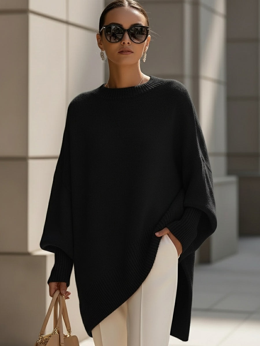 Jersey tipo poncho negro de corte amplio, con mangas largas y terminación asimétrica más larga en un lateral.