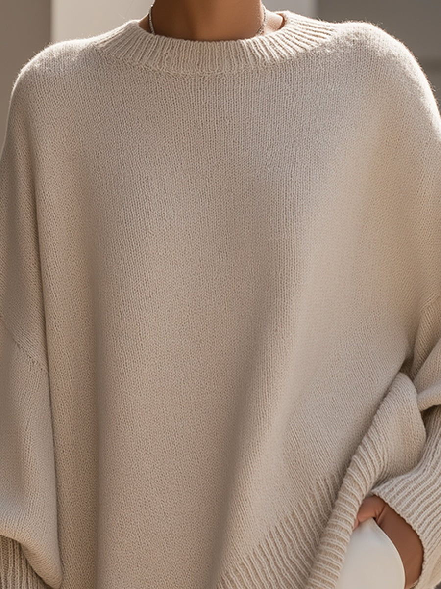 Detalle frontal del jersey beige con cuello redondo de canalé, cuerpo amplio y manga larga.