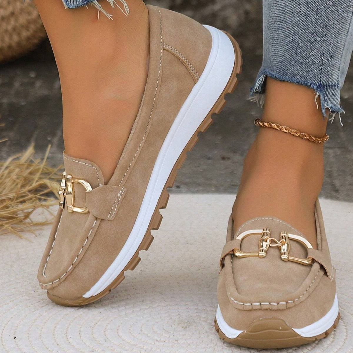 Mocasines beige con plataforma blanca, suela dentada y detalle metálico dorado en el empeine, vistos en primer plano.