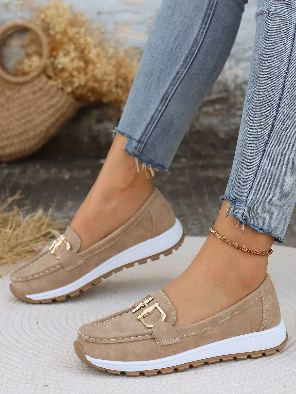 Mocasines beige de perfil sobre una superficie tejida, con silueta clásica, plataforma blanca y suela dentada marrón.