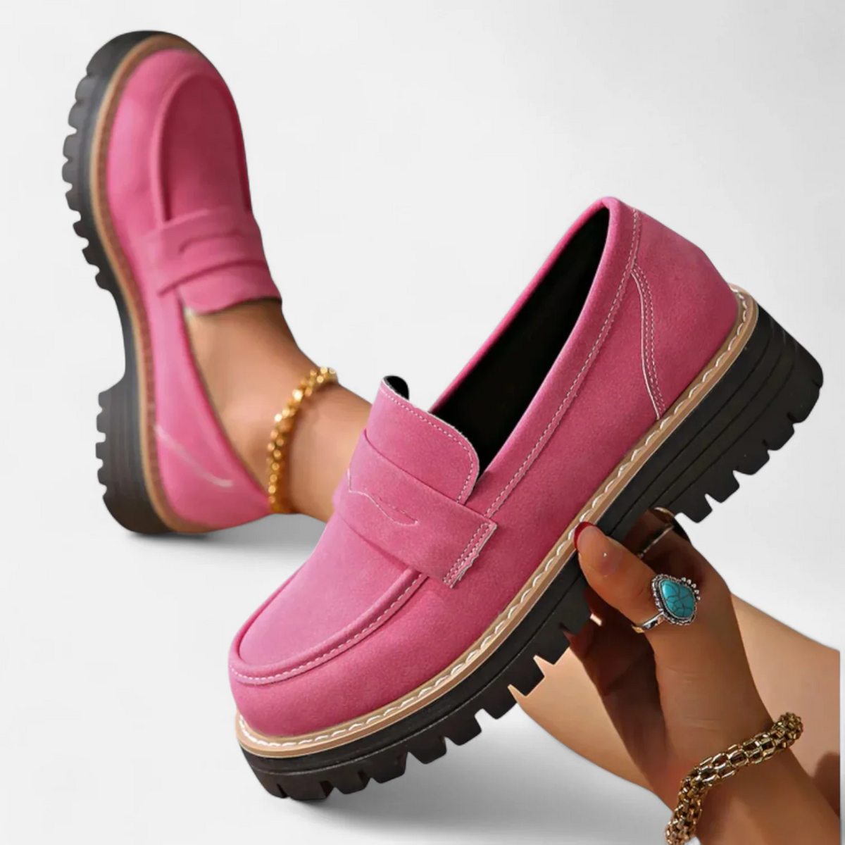 Mocasín rosa intenso sostenido en la mano para mostrar su perfil, la suela gruesa dentada y los pespuntes decorativos.