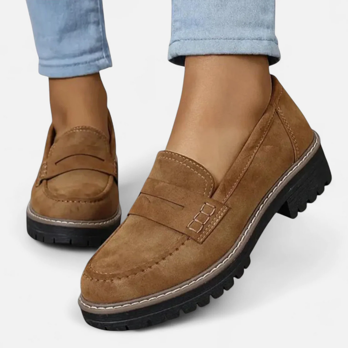 Mocasines marrón claro de mujer con costuras visibles en la puntera, tira decorativa y suela negra gruesa de tacos pronunciados.