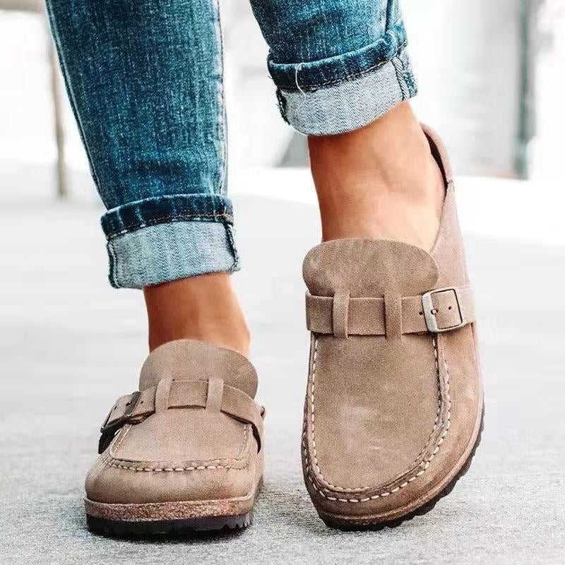 Mocasines planos en tono beige, vistos de frente y ligeramente desde arriba para destacar la puntera y la hebilla.