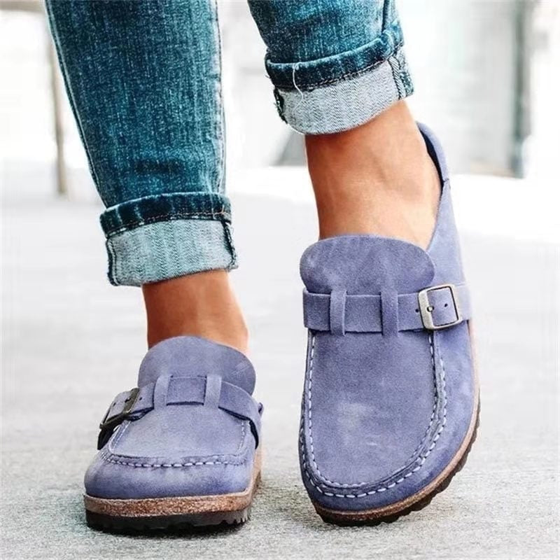 Mocasines planos en tono azul lavanda, combinados con vaqueros y mostrados desde una perspectiva frontal.