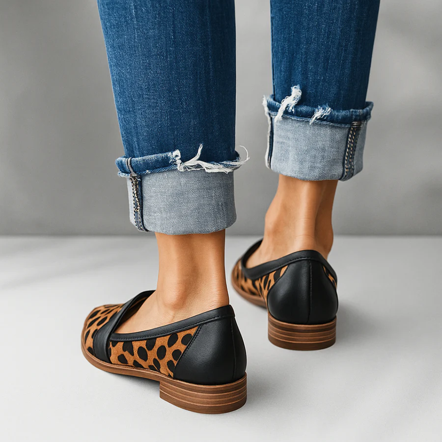 Parte trasera de unos mocasines con estampado animal, talón negro y suela marrón estratificada.