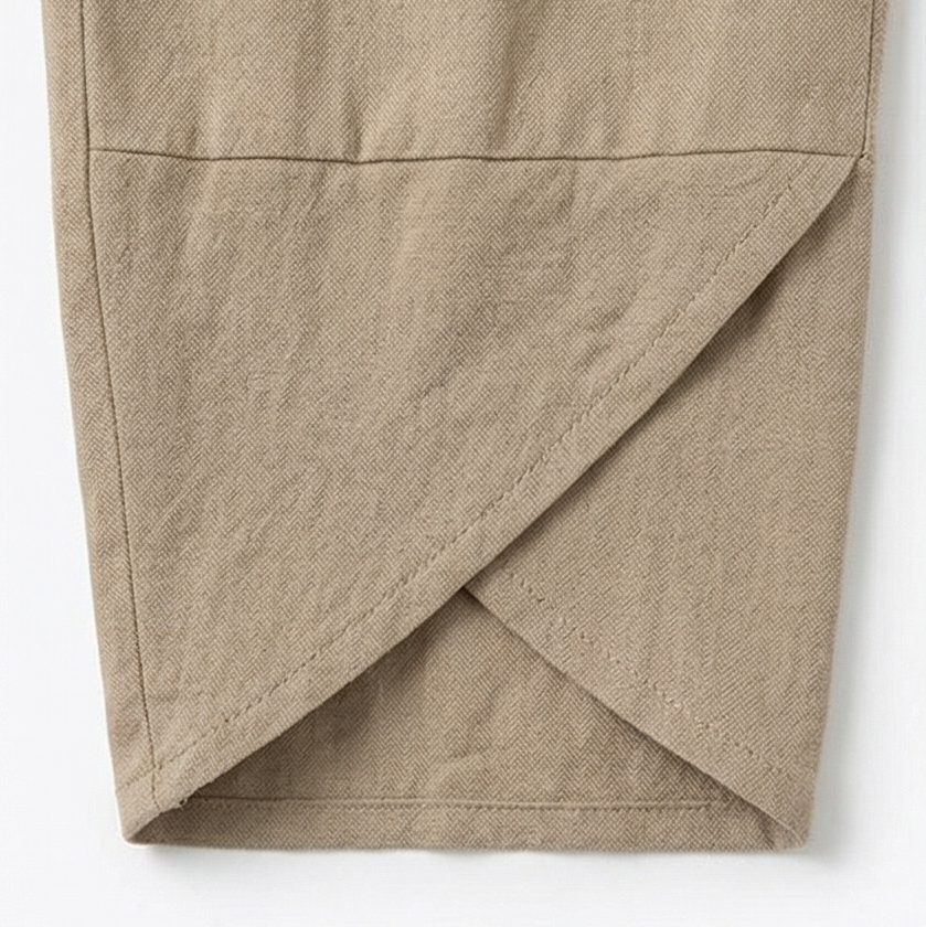Primer plano del bajo asimétrico cruzado del pantalón cropped beige.