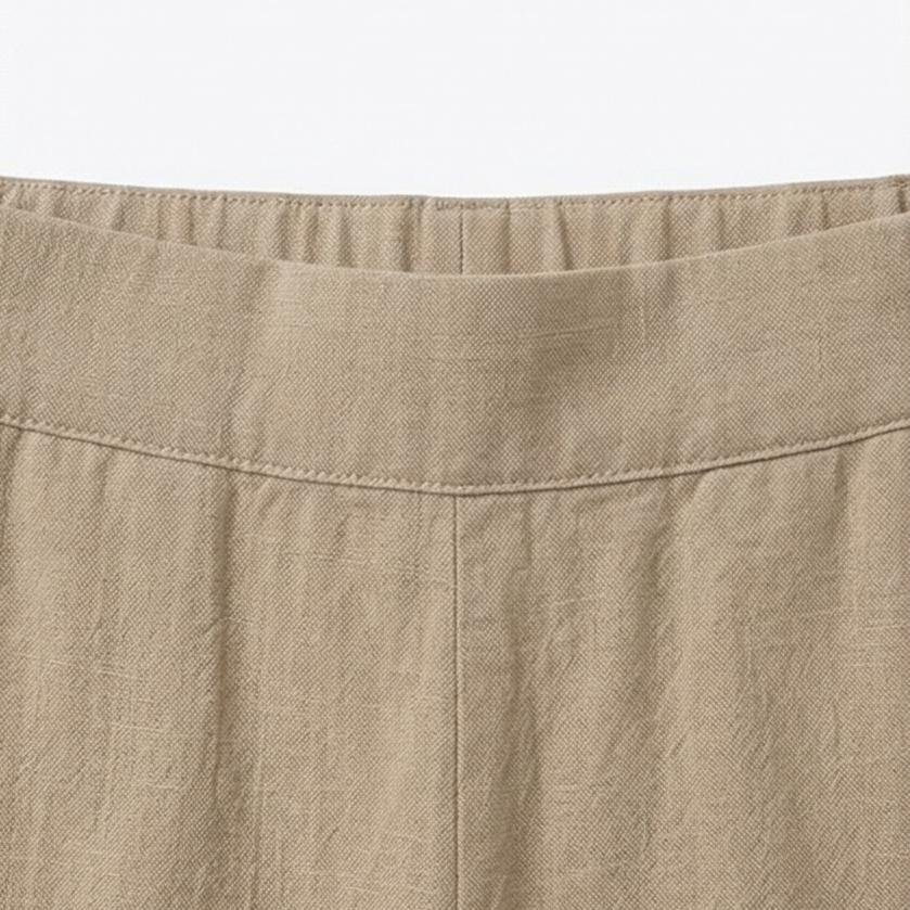 Detalle de la cintura elástica y las costuras superiores del pantalón beige.