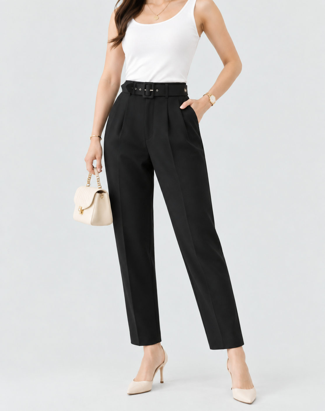Pantalón negro de tiro alto con pinzas delanteras, cinturón negro y pernera recta al tobillo, combinado con zapatos de tacón.