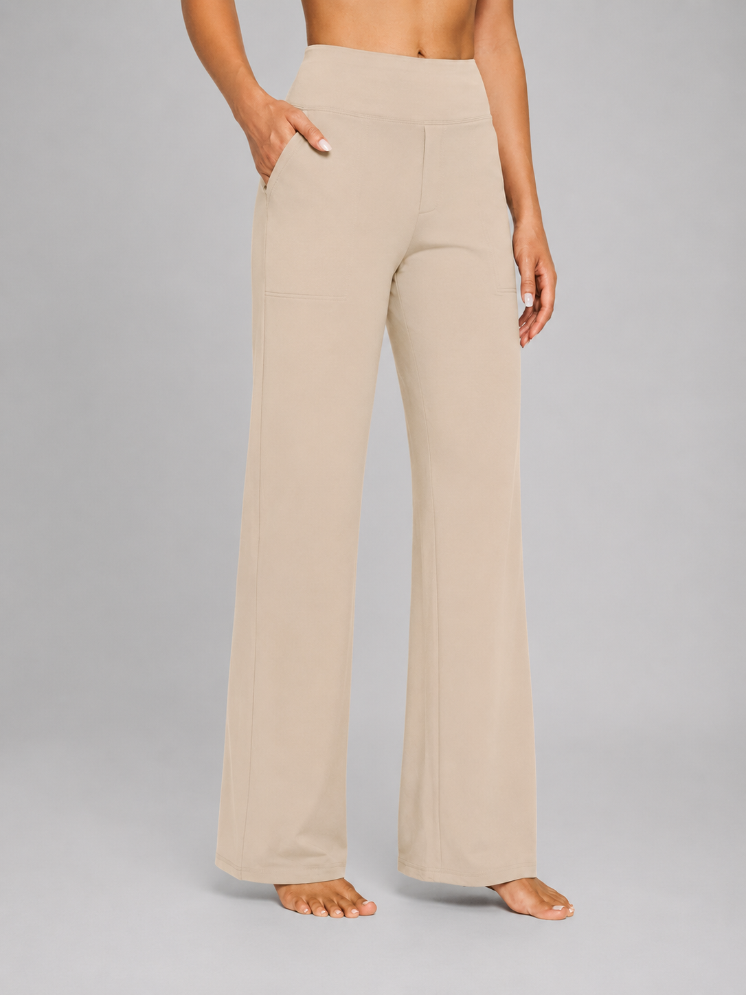 Pantalón de talle alto y pernera ancha en tono beige claro, visto de frente con la mano en el bolsillo lateral.