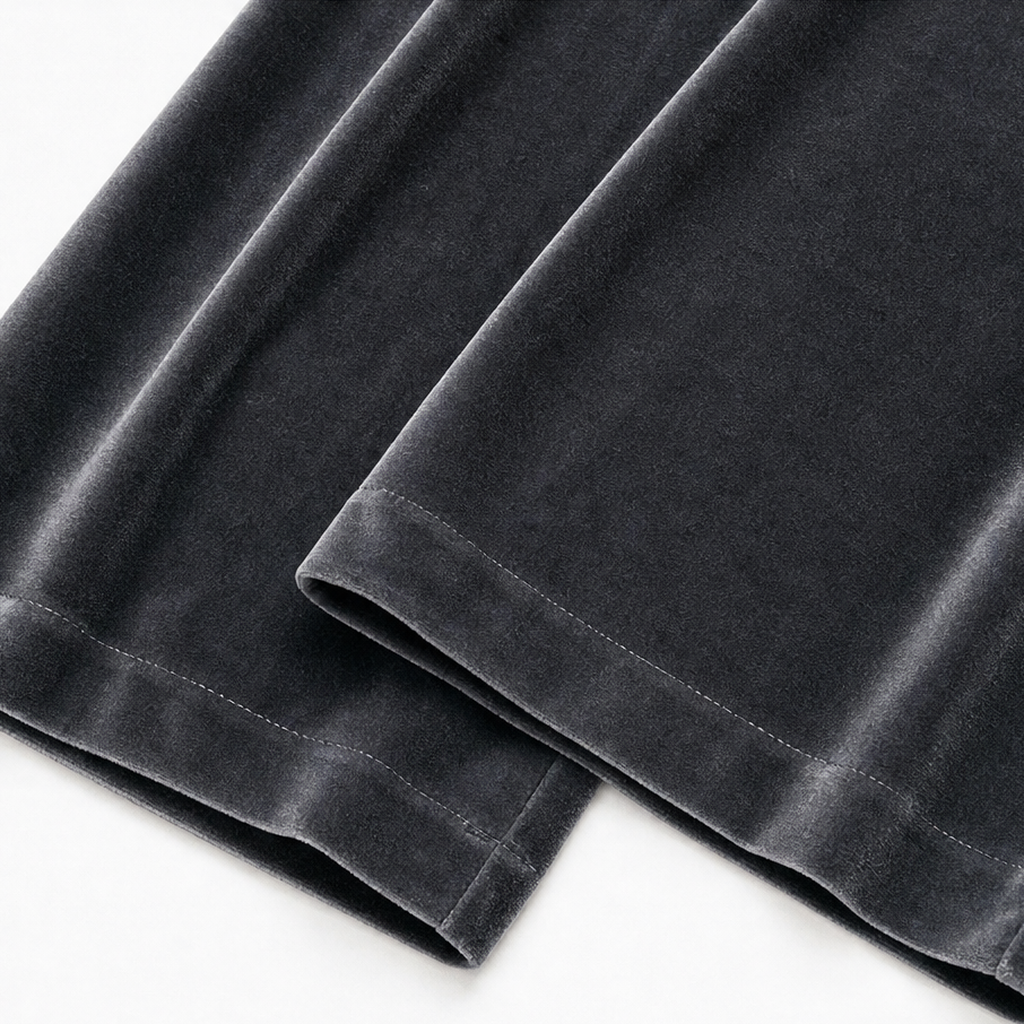 Detalle de los bajos amplios del pantalón gris oscuro y sus costuras de acabado.